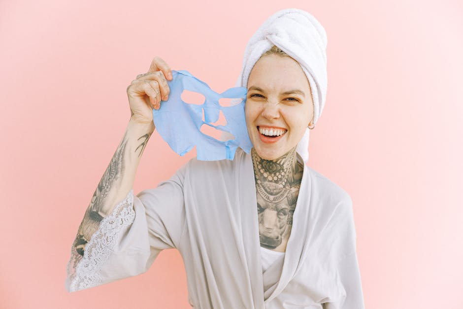 Happy woman holding a blue face mask, wrapped in a towel and smiling brightly