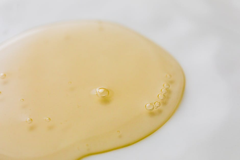 Close-up of a golden liquid with bubbles on a white surface, showcasing beauty and purity
