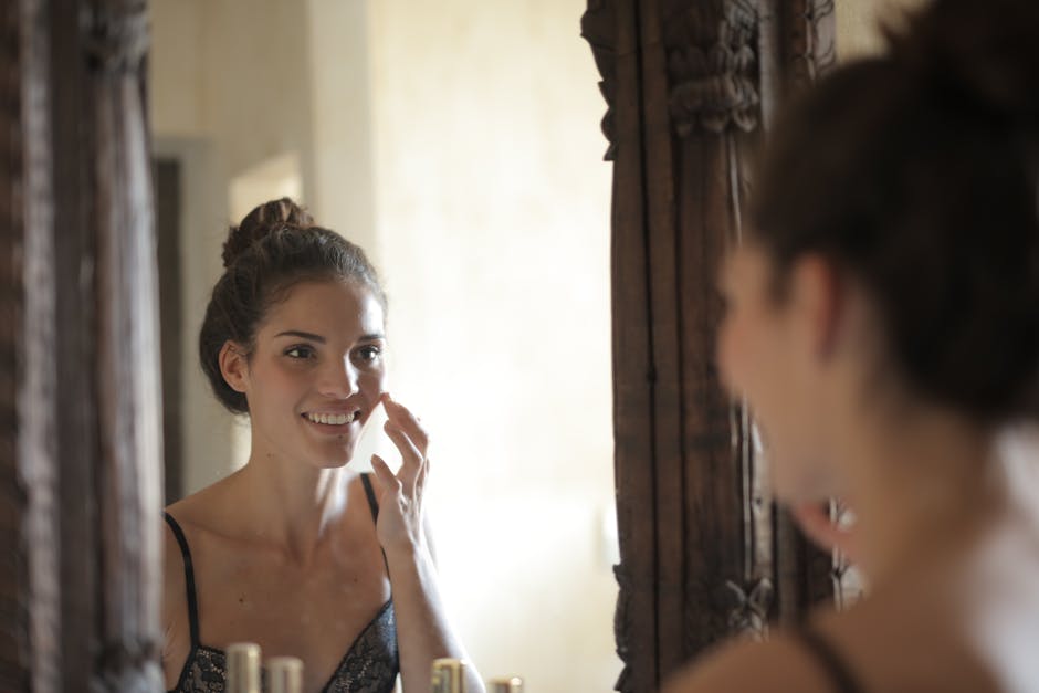 Young woman applying skincare and smiling at her reflection in a rustic mirror
