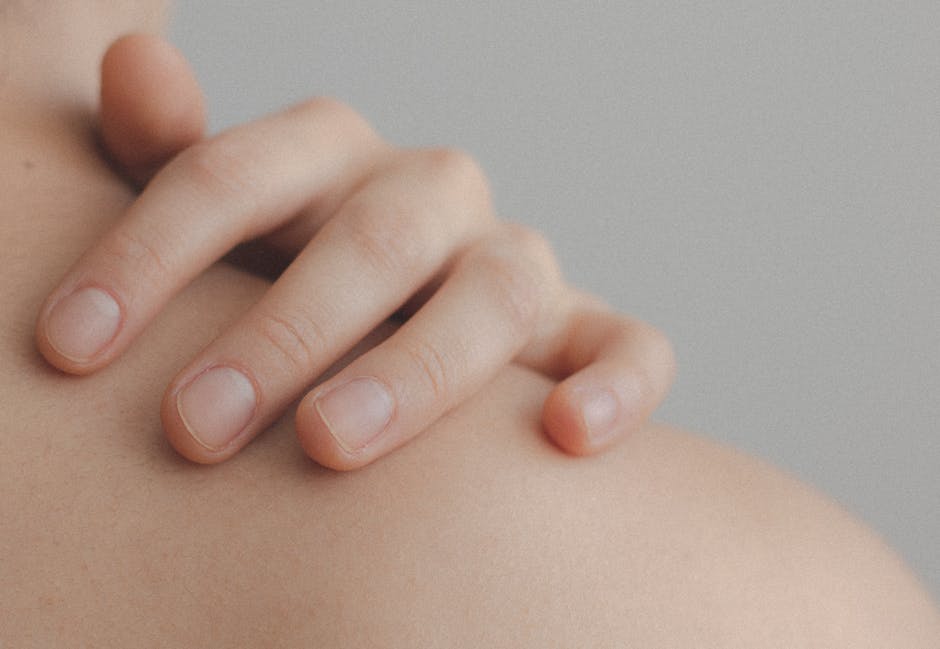 A gentle close-up of a hand resting on a person's shoulder, emphasizing skin texture